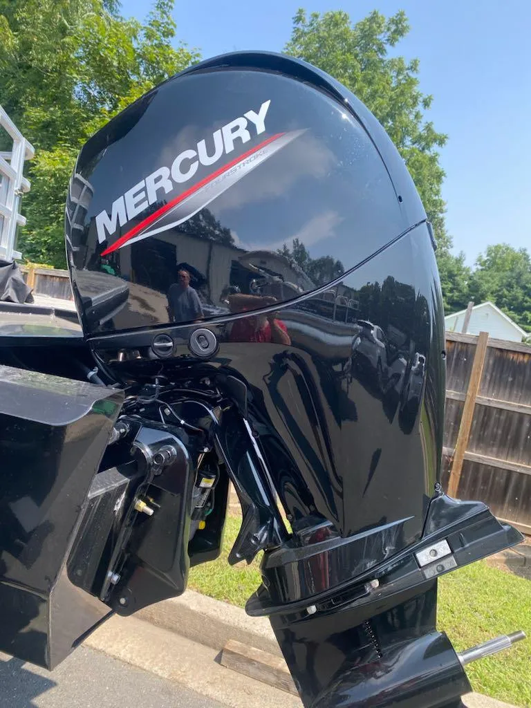 Slide: The Image of 2024 Ranger Reata 223C with Mercury outboard motor, parked outdoors. - 18