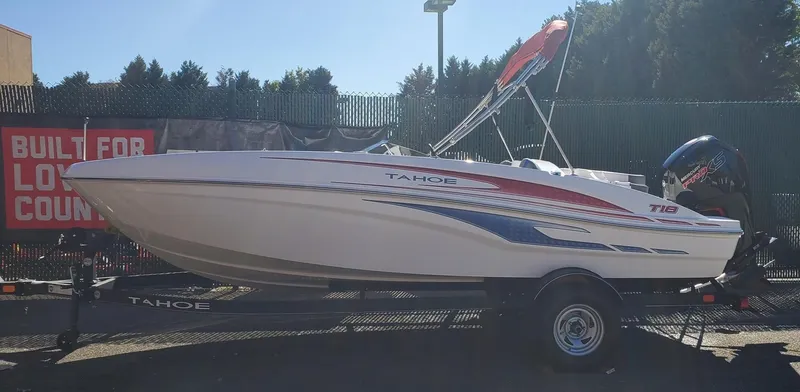 Slide: The Image of 2024 Tahoe T18 boat on trailer, displayed outdoors with promotional banner. - 0