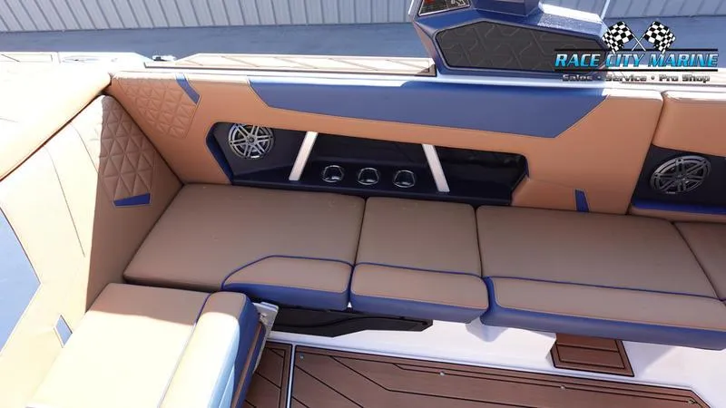Slide: The Image of 2025 Nautique Super Air Nautique GS22 interior with tan and blue seating, premium speakers. - 13