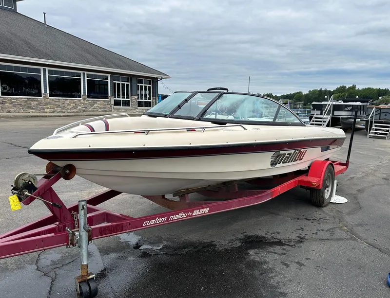 Slide: The Image of 2000 Malibu Response LXi boat on a red trailer, parked near a building. - 4
