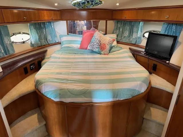 Slide: The Image of 2001 Carver 396 Motoryacht bedroom with striped bedding, pillows, and a small TV. - 10