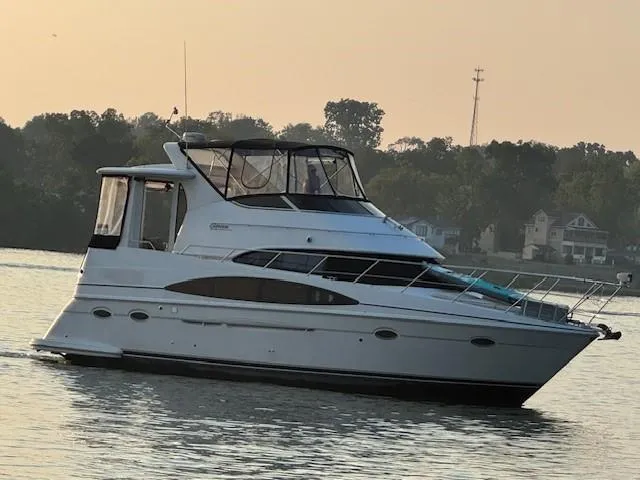 Slide: The Image of 2001 Carver 396 Motoryacht on calm water at sunset, surrounded by trees and houses. - 21