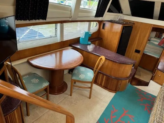 Slide: The Image of Interior of 2001 Carver 396 Motoryacht with dining area, wooden furnishings, and teal accents. - 3