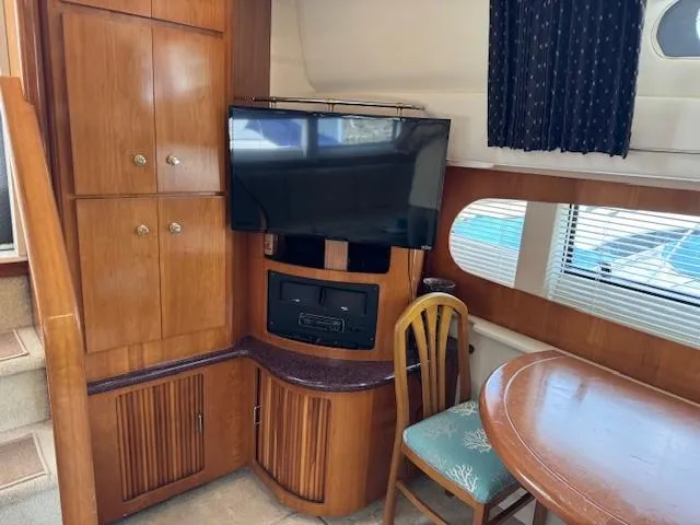 Slide: The Image of Interior of 2001 Carver 396 Motoryacht with TV, wooden cabinets, and dining area. - 9
