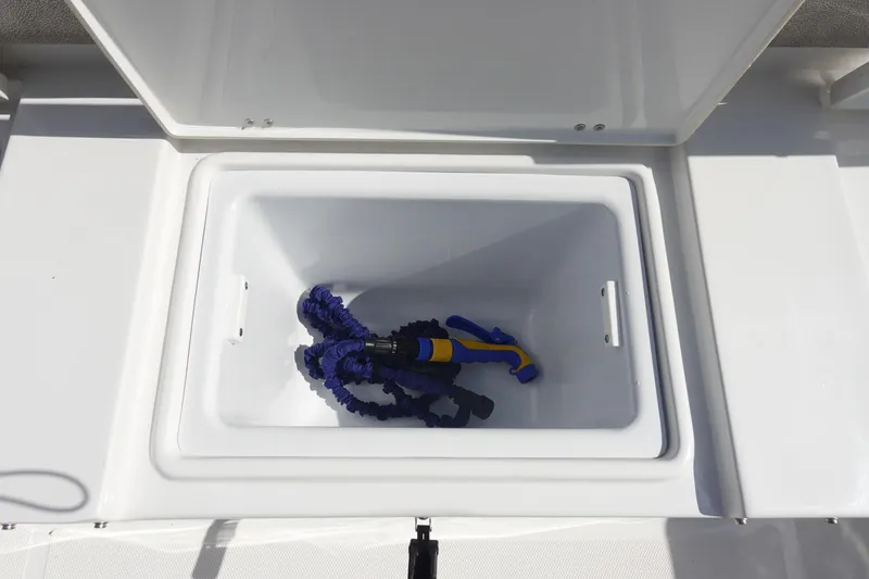 Slide: The Image of Open storage compartment on 2025 Sea Hunt Ultra 265 SE boat with coiled hose inside. - 12