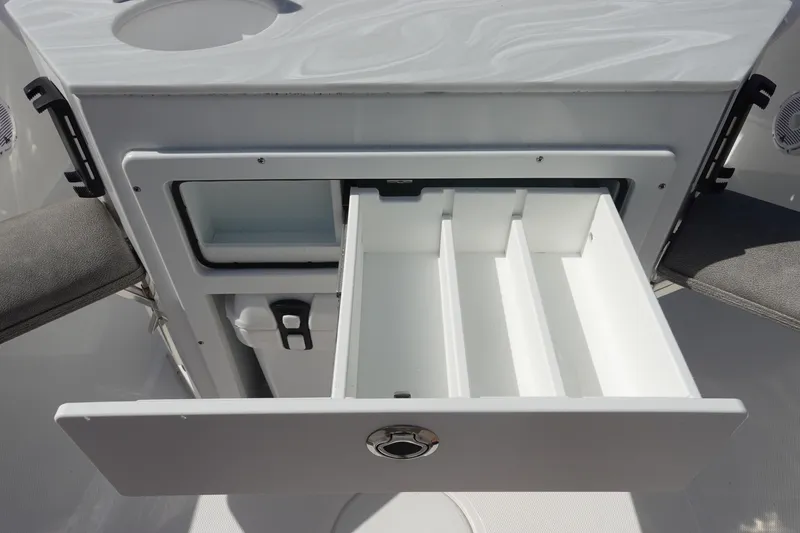 Slide: The Image of 2025 Sea Hunt Ultra 265 SE boat storage compartment with open drawer and cup holder. - 17