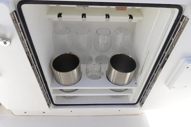 Slide: The Image of Storage compartment with glasses and metal containers on Sea Hunt Ultra 265 SE, 2025 model. - 20