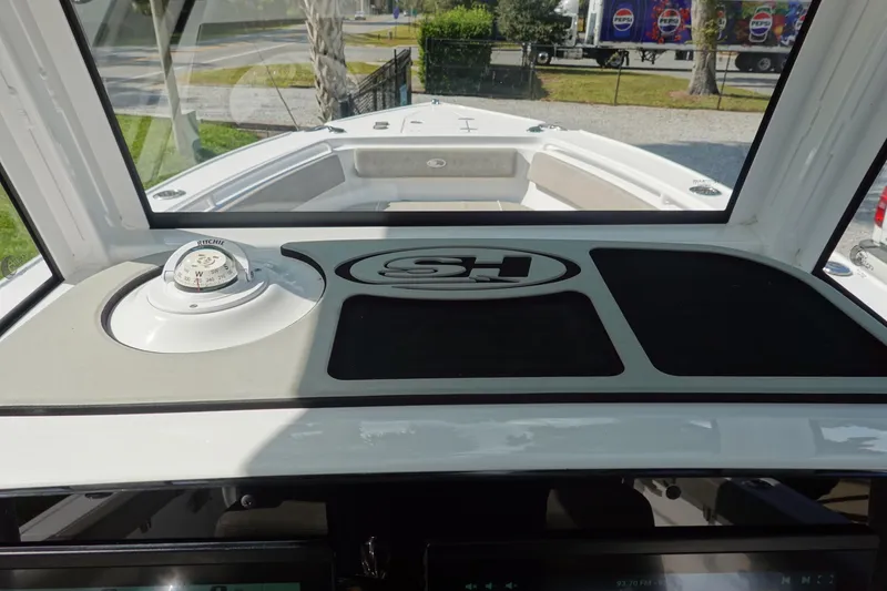 Slide: The Image of 2025 Sea Hunt Ultra 265 SE boat dashboard with compass and logo, viewed from cockpit. - 27
