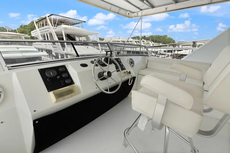 Slide: The Image of 2001 Stardust Cruisers houseboat helm with steering wheel and controls, docked under blue sky. - 16