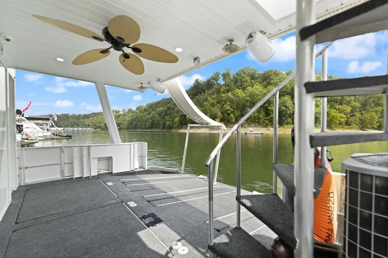 Slide: The Image of Houseboat deck with spiral staircase, ceiling fan, and scenic lake view. Stardust Cruisers 2001 model. - 20