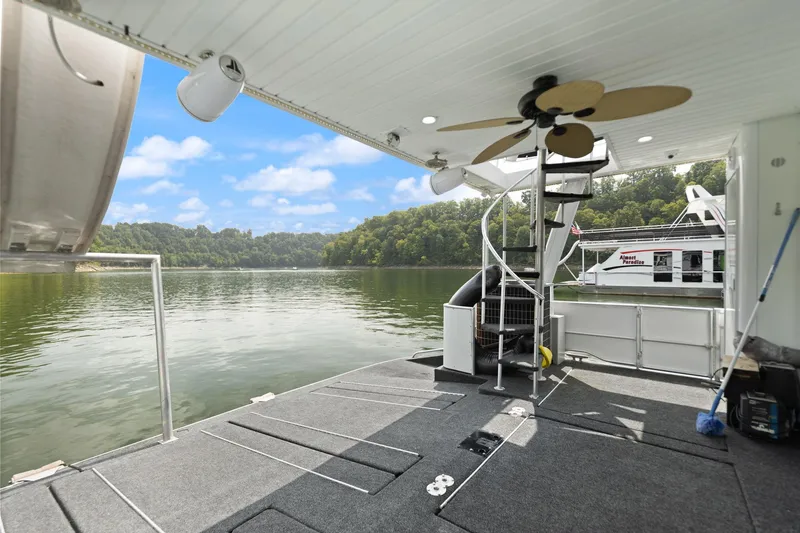 Slide: The Image of Houseboat deck with spiral staircase, ceiling fan, and scenic lake view. Stardust Cruisers 18 x 100, 2001. - 21