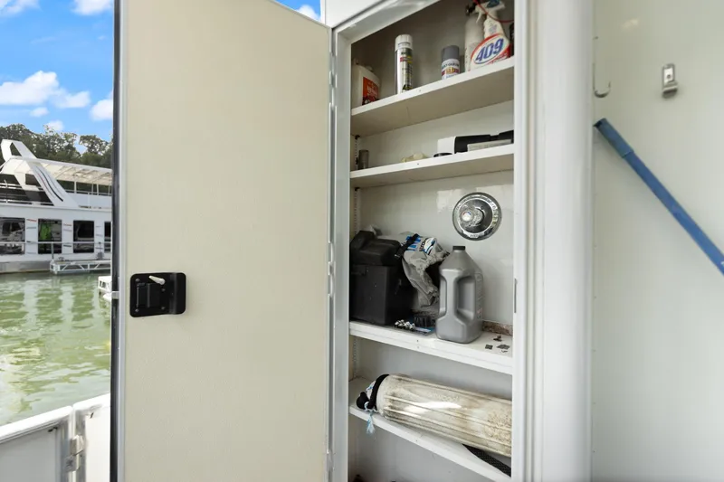 Slide: The Image of Open storage cabinet on 2001 Stardust Cruisers houseboat, containing cleaning supplies and tools. - 25