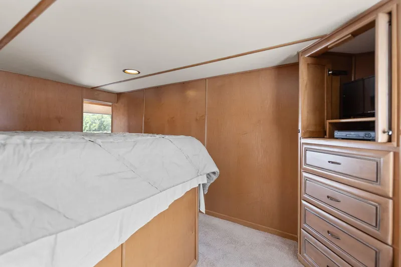 Slide: The Image of Interior of 2001 Stardust Cruisers houseboat bedroom with bed, wooden cabinets, and small window. - 42