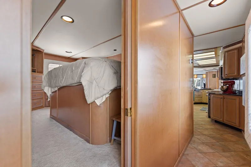 Slide: The Image of Interior of 2001 Stardust Cruisers houseboat, featuring bedroom and kitchen with wood paneling. - 46