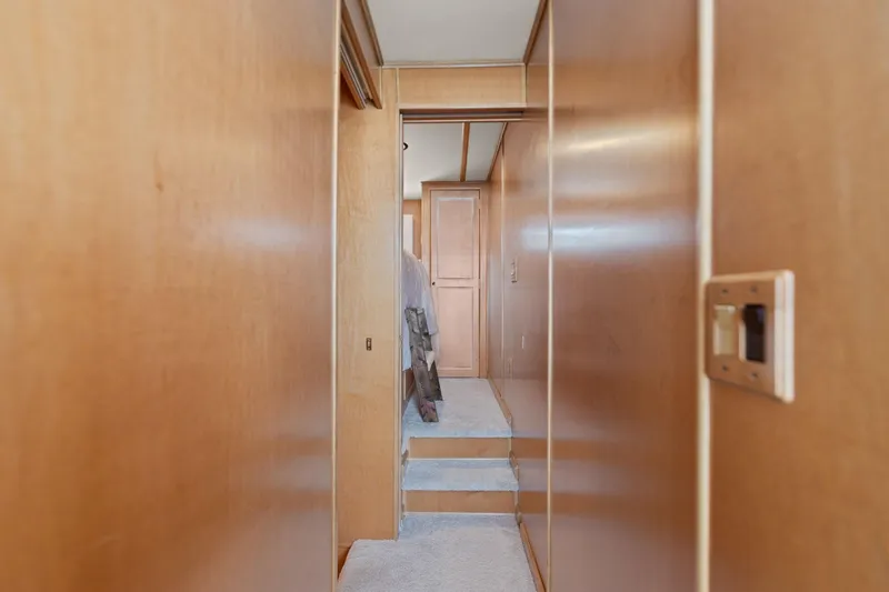 Slide: The Image of Narrow hallway inside 2001 Stardust Cruisers 18 x 100 houseboat with wooden walls and carpeted steps. - 47