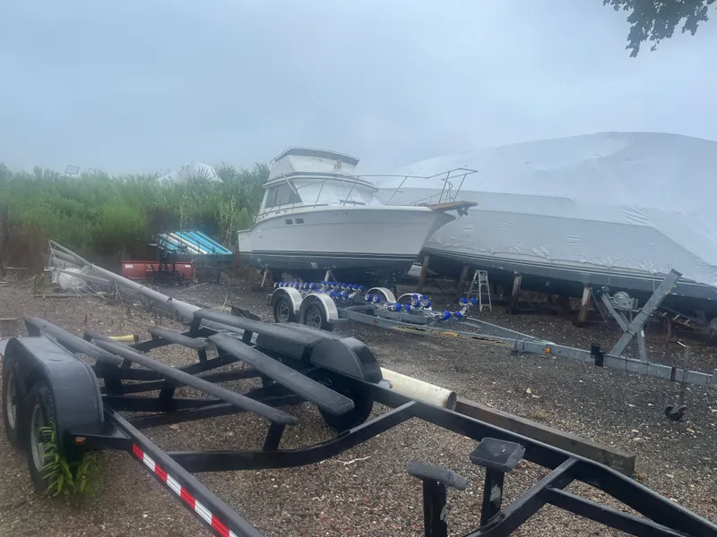 The Image of 1986 Trojan F32 boat on trailer in outdoor storage area. - 2