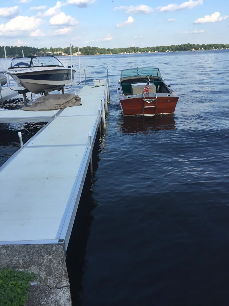 Slide: The Image of 1966 Century Resorter boat docked on a calm lake under a partly cloudy sky. - 8