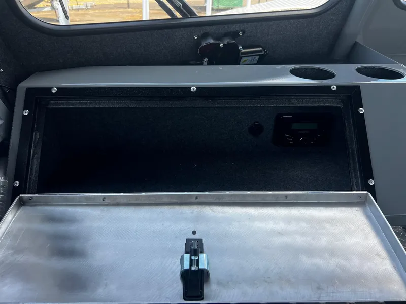 Slide: The Image of 2024 Thunder Jet 24 Alexis Pro interior storage compartment with open lid and cup holders. - 27