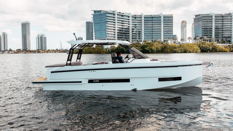 Slide: The Image of 2025 De Antonio Yachts D32 OPEN on water, modern cityscape in background. - 1