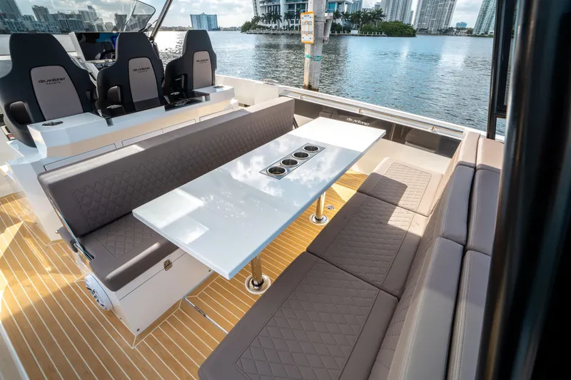 Slide: The Image of De Antonio Yachts D32 OPEN 2025, luxury seating area with table on deck, waterfront view. - 18