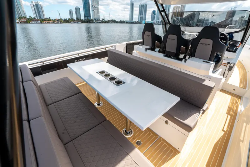 Slide: The Image of De Antonio Yachts D32 OPEN 2025, luxurious seating area with table, city skyline view. - 19