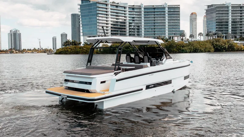 Slide: The Image of De Antonio Yachts D32 OPEN 2025 cruising near modern waterfront buildings. - 2