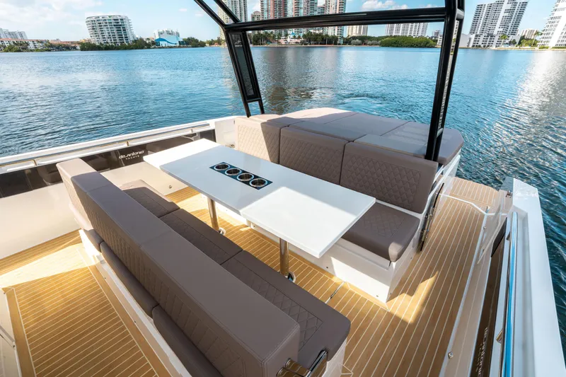 Slide: The Image of De Antonio Yachts D32 OPEN 2025, luxurious deck seating with table, scenic waterfront view. - 20