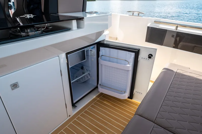 Slide: The Image of Interior of 2025 De Antonio Yachts D32 OPEN with open mini fridge and seating area. - 25
