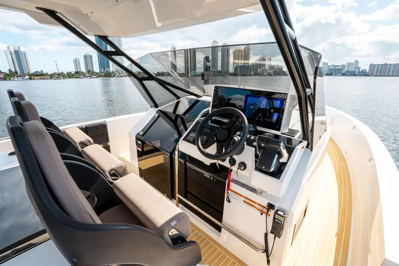 Slide: The Image of 2025 De Antonio Yachts D32 OPEN helm with modern controls and city skyline backdrop. - 29