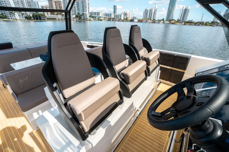 Slide: The Image of 2025 De Antonio Yachts D32 OPEN interior with modern seating and steering, city skyline in background. - 33