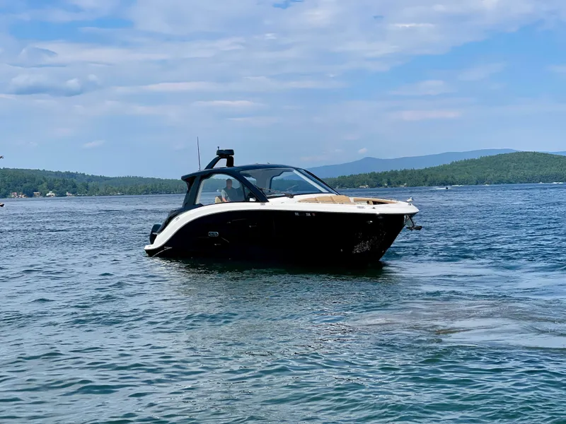 Slide: The Image of 2023 Sea Ray Sundancer 370 OB cruising on a serene lake under a partly cloudy sky. - 1