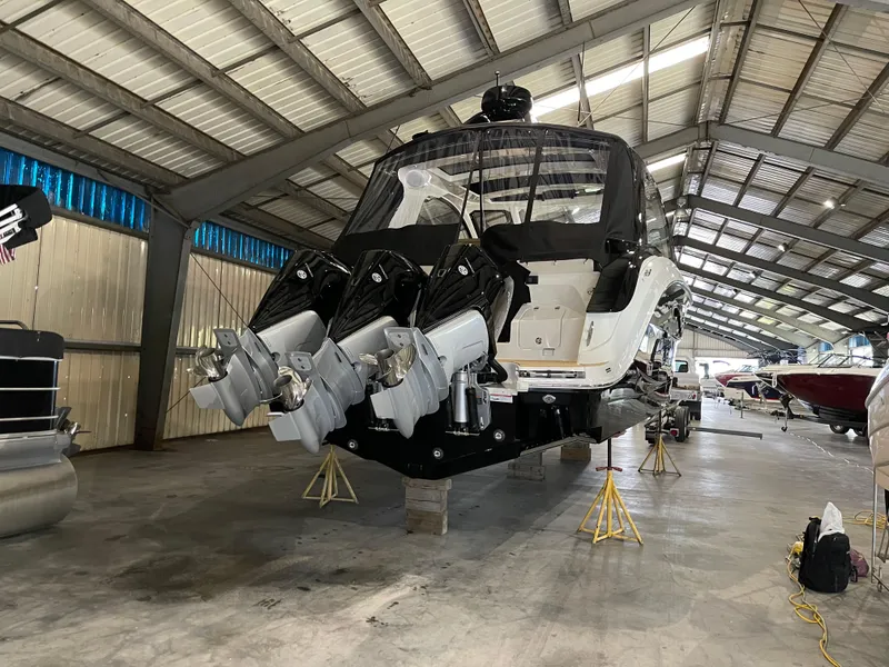 Slide: The Image of 2023 Sea Ray Sundancer 370 OB in a boat storage facility, showcasing triple outboard engines. - 10