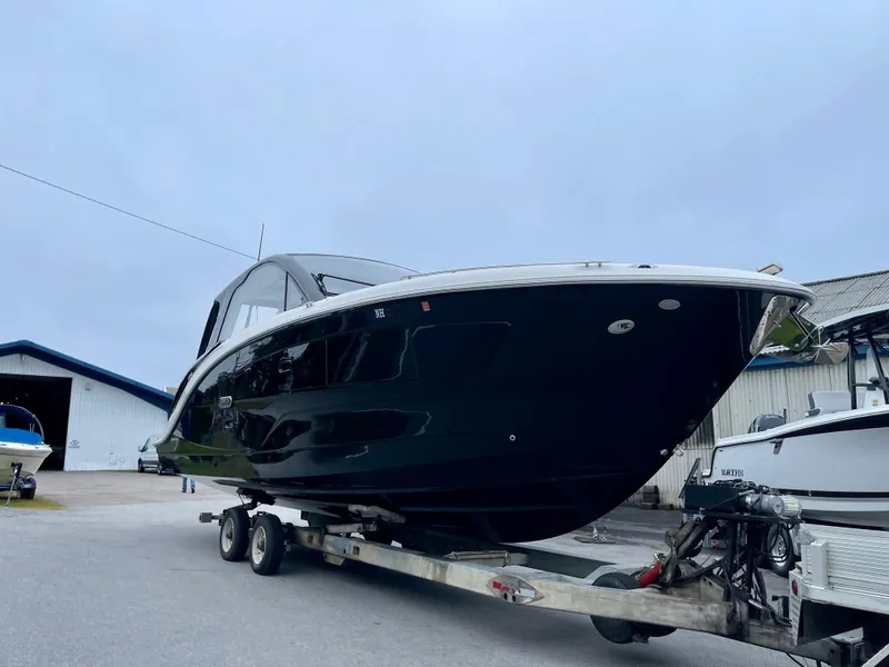Slide: The Image of 2023 Sea Ray Sundancer 370 OB on trailer, sleek black design, parked outdoors. - 8