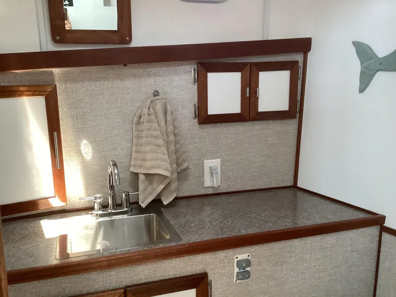 Slide: The Image of Compact boat kitchen with sink, towel, and wooden cabinets in a 2021 Willis Beal 35 Extended Pilothouse. - 48