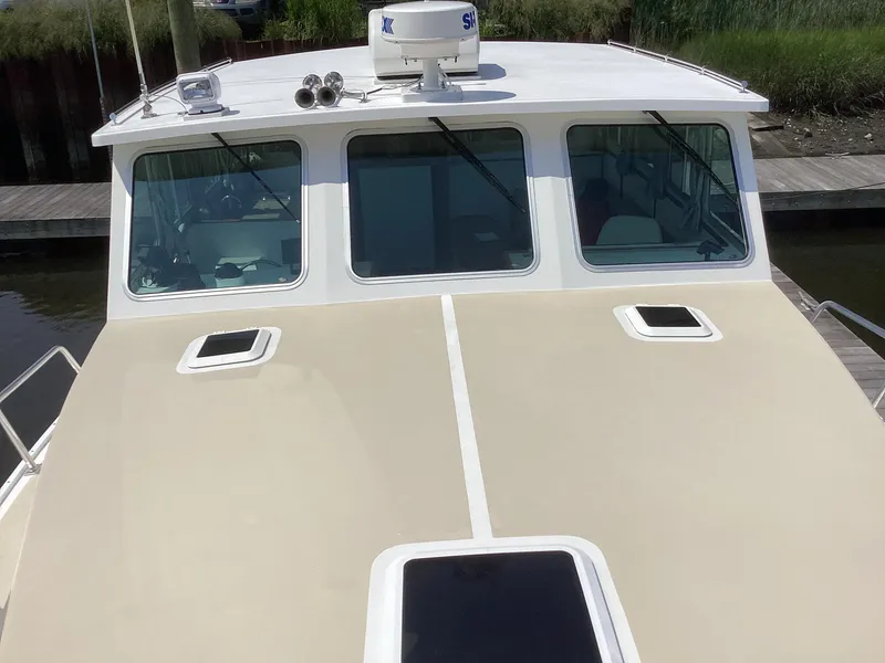 Slide: The Image of 2021 Willis Beal 35 Extended Pilothouse boat, beige deck, docked by the water. - 8