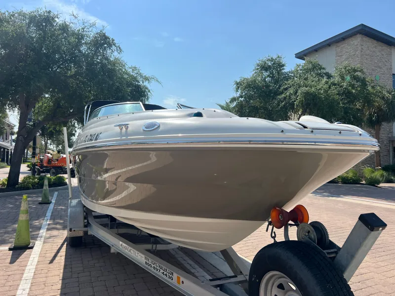 Slide: The Image of 2006 Sea Ray 240 Sundeck boat on trailer, parked outdoors under clear sky. - 2