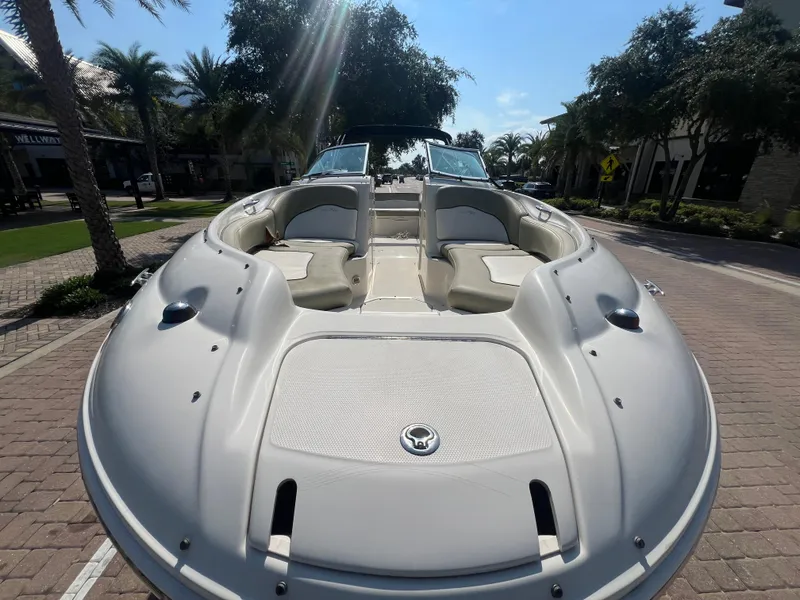 Slide: The Image of 2006 Sea Ray 240 Sundeck boat with spacious seating, parked on a sunny street. - 4