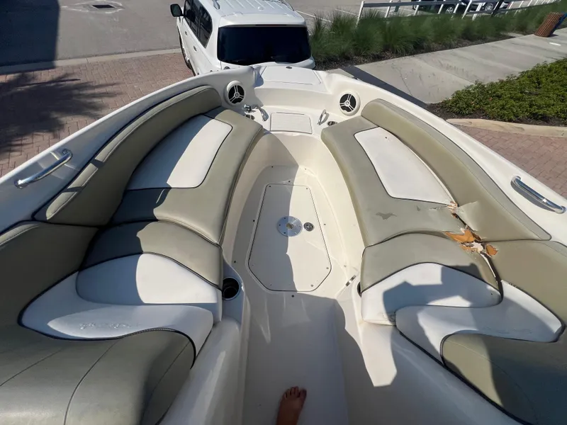 Slide: The Image of 2006 Sea Ray 240 Sundeck interior with beige seating, parked near a white vehicle. - 8