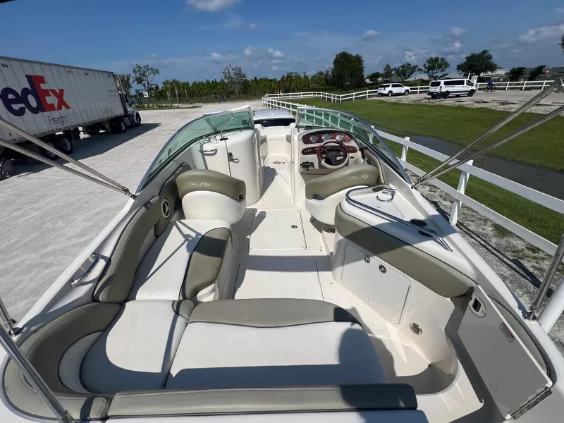 Slide: The Image of 2006 Sea Ray 240 Sundeck boat interior with seating and steering wheel, parked outdoors. - 9