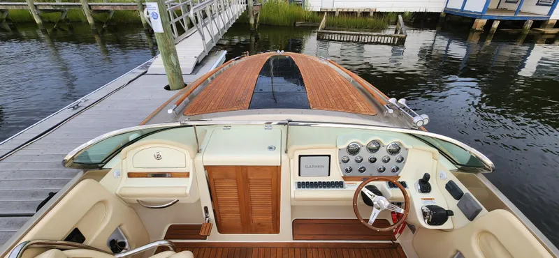Slide: The Image of 2017 Chris-Craft Corsair 32 boat interior with wooden dashboard and steering wheel at dock. - 10