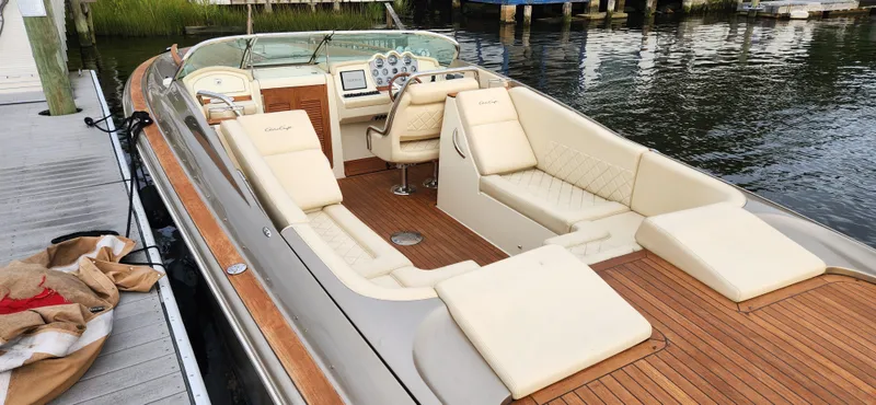Slide: The Image of 2017 Chris-Craft Corsair 32 boat with luxurious seating and wooden deck by the water. - 12