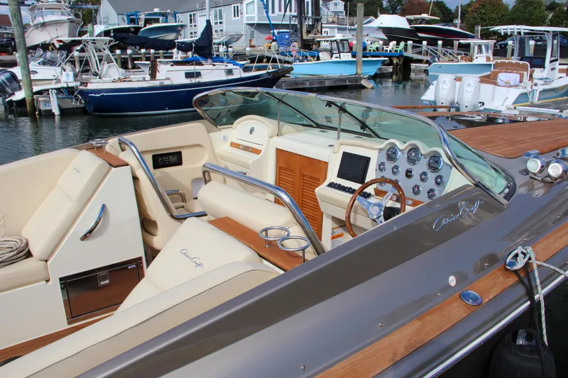 Slide: The Image of 2017 Chris-Craft Corsair 32 boat interior at marina, featuring luxurious seating and dashboard. - 2