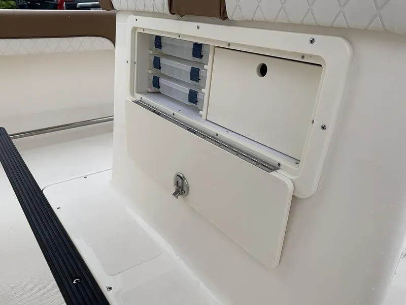 Slide: The Image of 2025 Pioneer SPORTFISH 222 boat storage compartment with tackle boxes. - 14