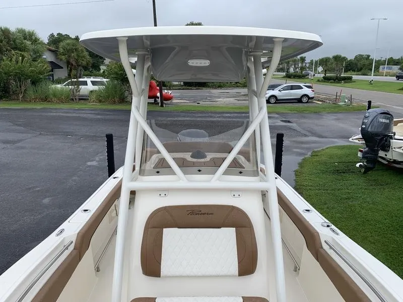 Slide: The Image of 2025 Pioneer SPORTFISH 222 boat with T-top and seating, parked outdoors. - 25