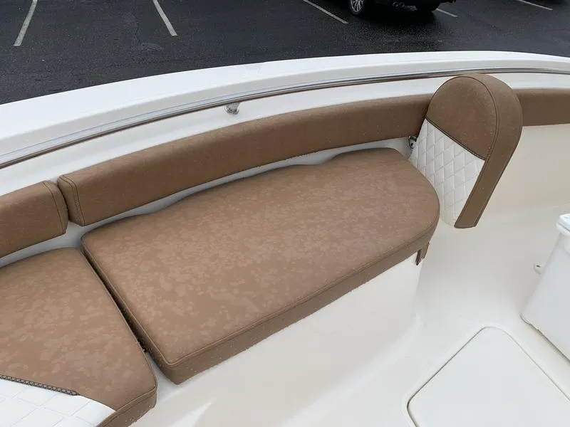 Slide: The Image of 2025 Pioneer SPORTFISH 222 boat with tan cushioned seating in a parking lot. - 27