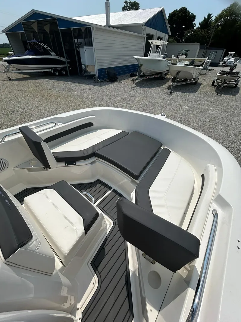 Slide: The Image of 2022 Bayliner Trophy T20CX boat with cushioned seating, docked near a boatyard. - 2