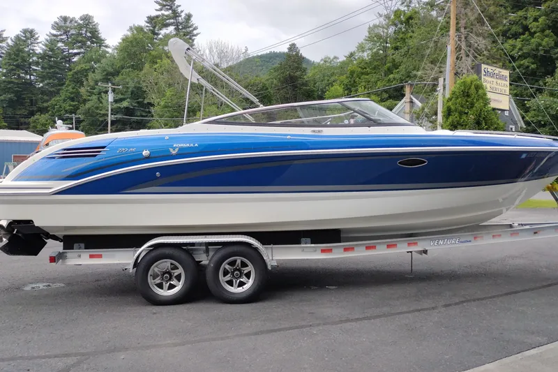 The Image of 2016 Formula 270 Bowrider boat on trailer, blue and white design, outdoor setting. - 1