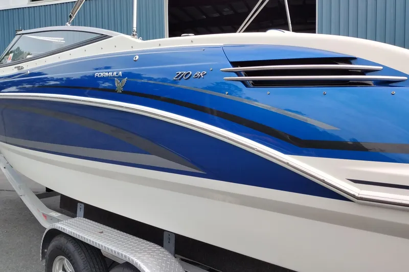 Slide: The Image of 2016 Formula 270 Bowrider boat with sleek blue and white design on a trailer. - 12
