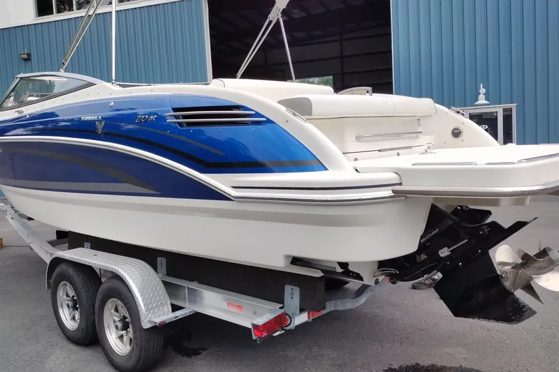 Slide: The Image of 2016 Formula 270 Bowrider boat on trailer, blue and white design, parked near blue building. - 13