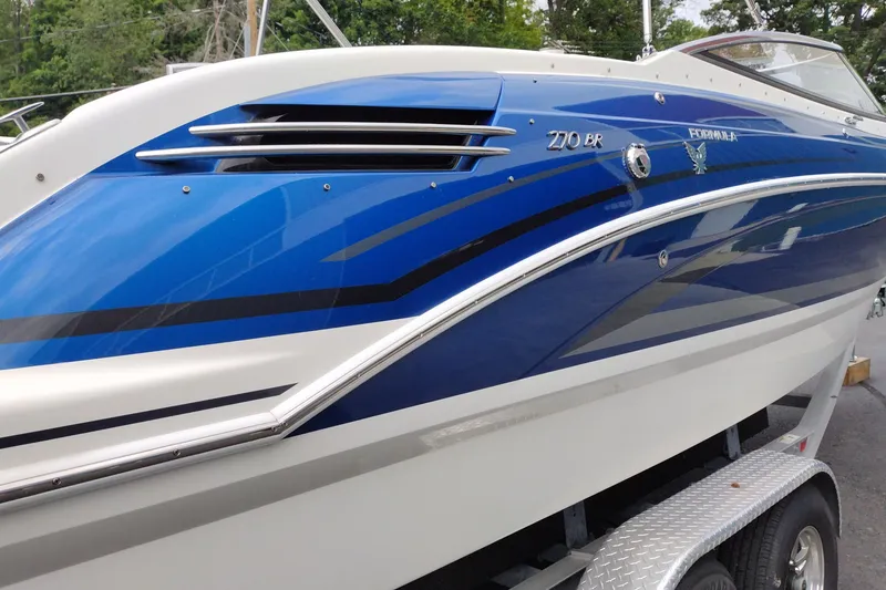 Slide: The Image of 2016 Formula 270 Bowrider boat with sleek blue and white design on trailer. - 3